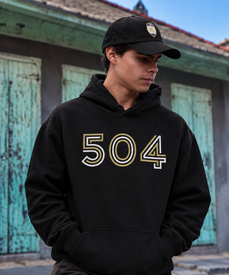 Man wearing black 504 hoodie against blurred turquoise New Orleans shutters